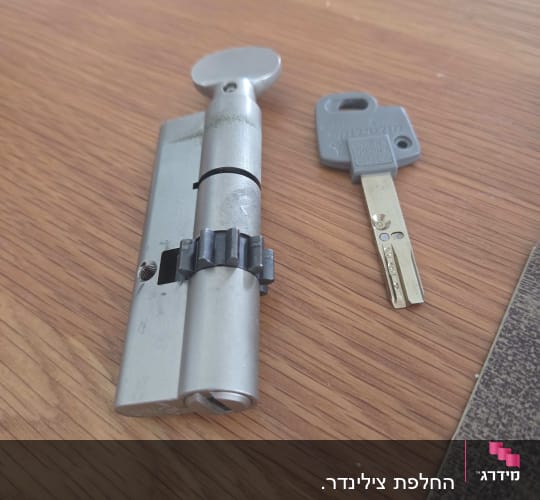 צילינדר מנעול עם כפתור פרפר ומפתח תואם על משטח עץ